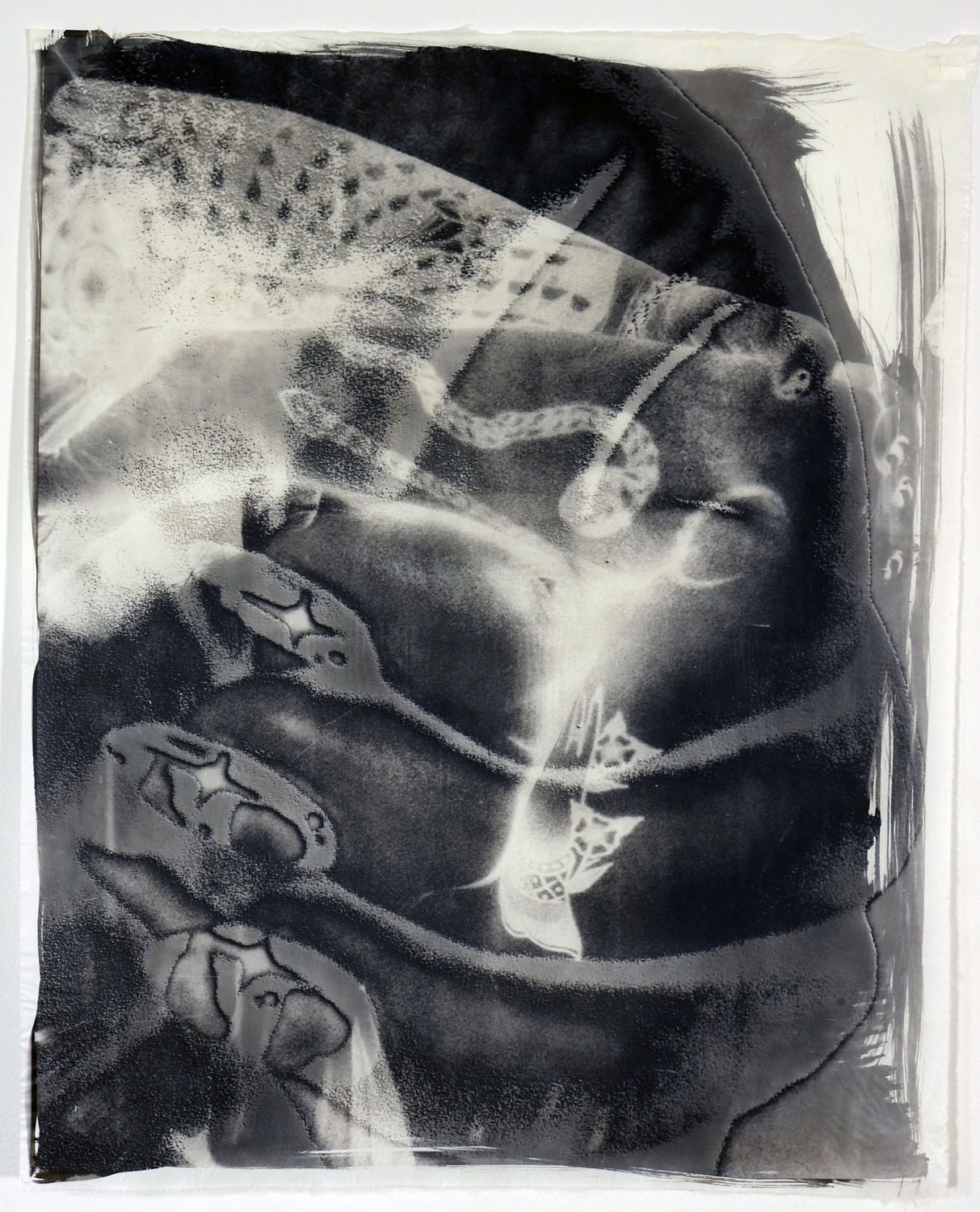 A double exposed print of a large hand embracing a woman with her arms crossed. The idea is that we must learn to embrace ourselves, especially in times of trouble.