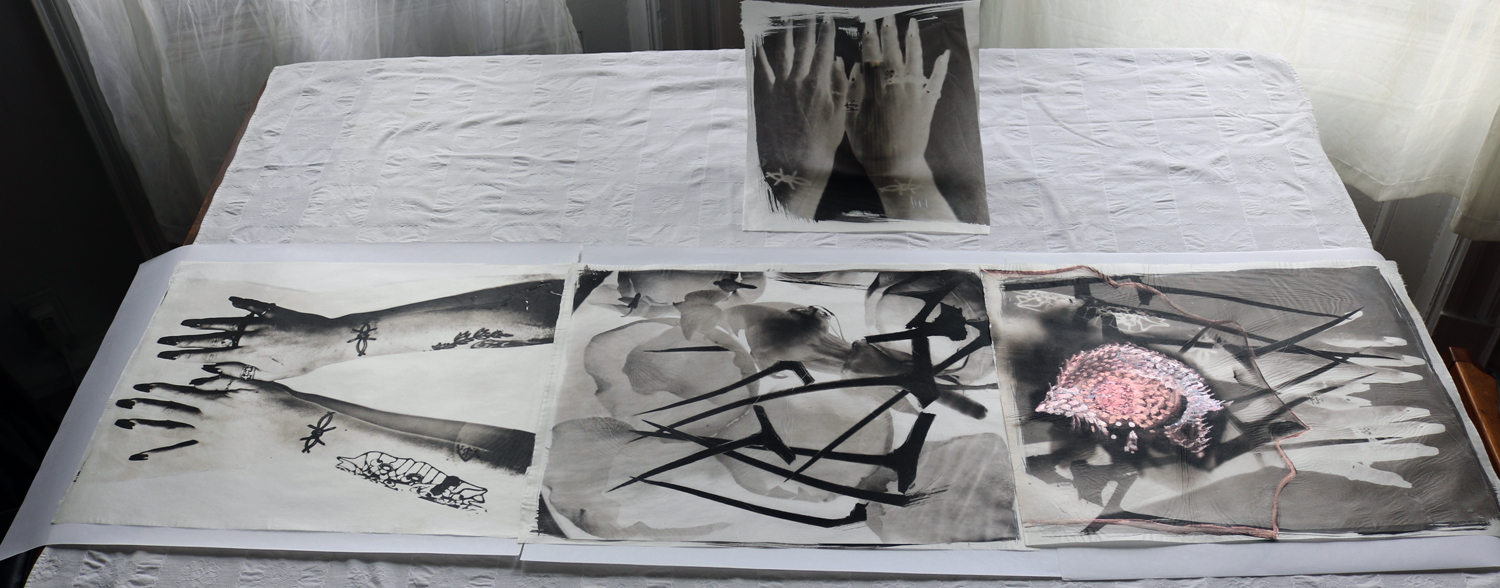 Installation of prints of a woman's arms where she has tattooed images of barbed wire, acting as a protective symbol.
